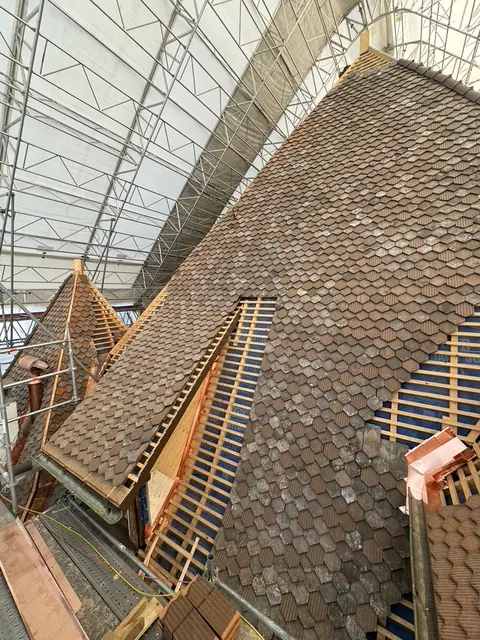 Grande toiture en tuiles d'un bâtiment ancien de Nyon, sous échafaudage.